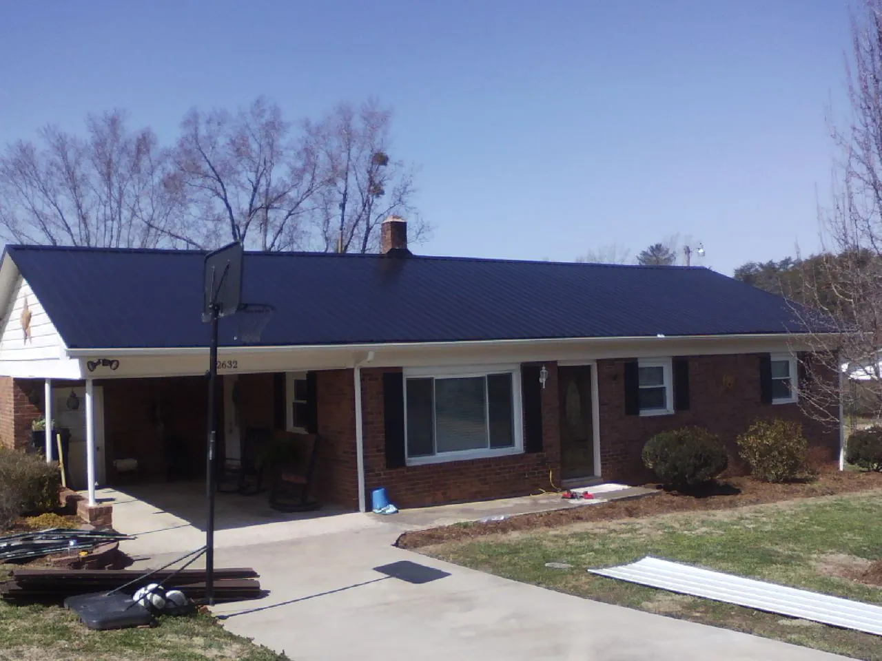 Finished dark blue metal roof on a brick ranch with a carport in New Suffolk