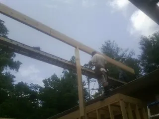 Carpenter setting a ridge beam over a new addition frame — Ice Dam Removal by Roofing Brothers in New Suffolk