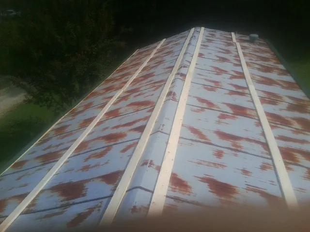 Rusted metal roof panels with new wood purlins before replacement — Storm Damage Roof Repair in New Suffolk by Roofing Brothers