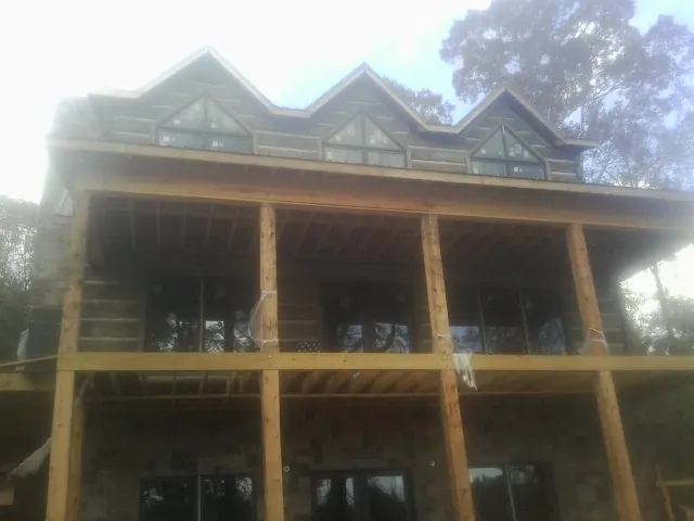 Dormers and porch framing on a large log home under construction — Roof Coating work by our crew in New Suffolk