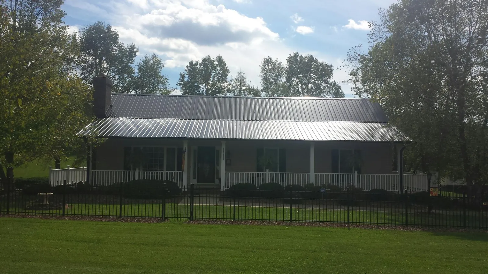 Gray metal roof on a brick ranch with a full width front porch — Gutter Guard Installation work by our crew in New Suffolk