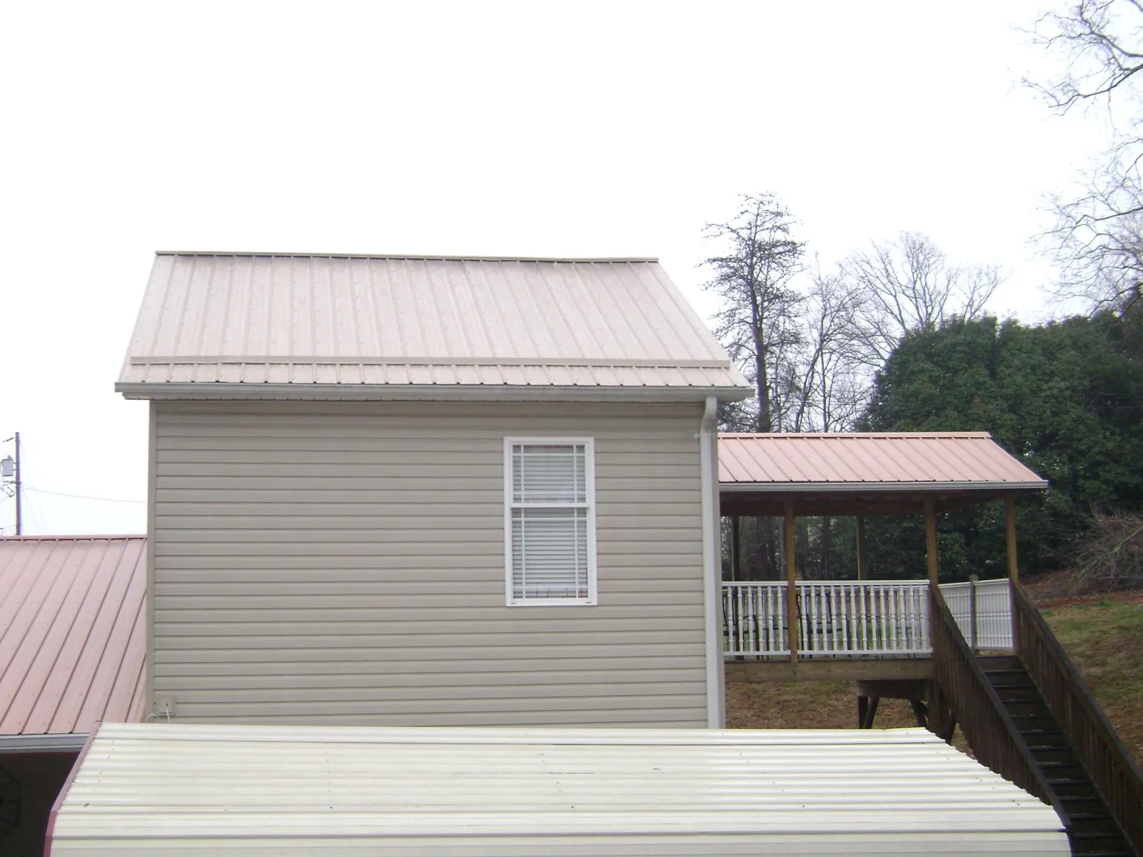 Tan metal roofs on a two story addition and attached porch, from a Roof Replacement job in New Suffolk