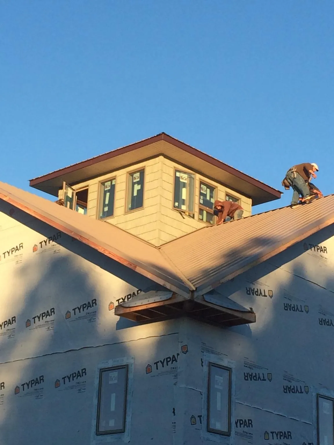 Roofers working around a rooftop cupola on a new metal roof at sunset — Roof Waterproofing in New Suffolk by Roofing Brothers